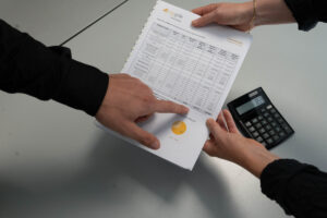 Deux personnes examinent un document financier avec un calculateur.