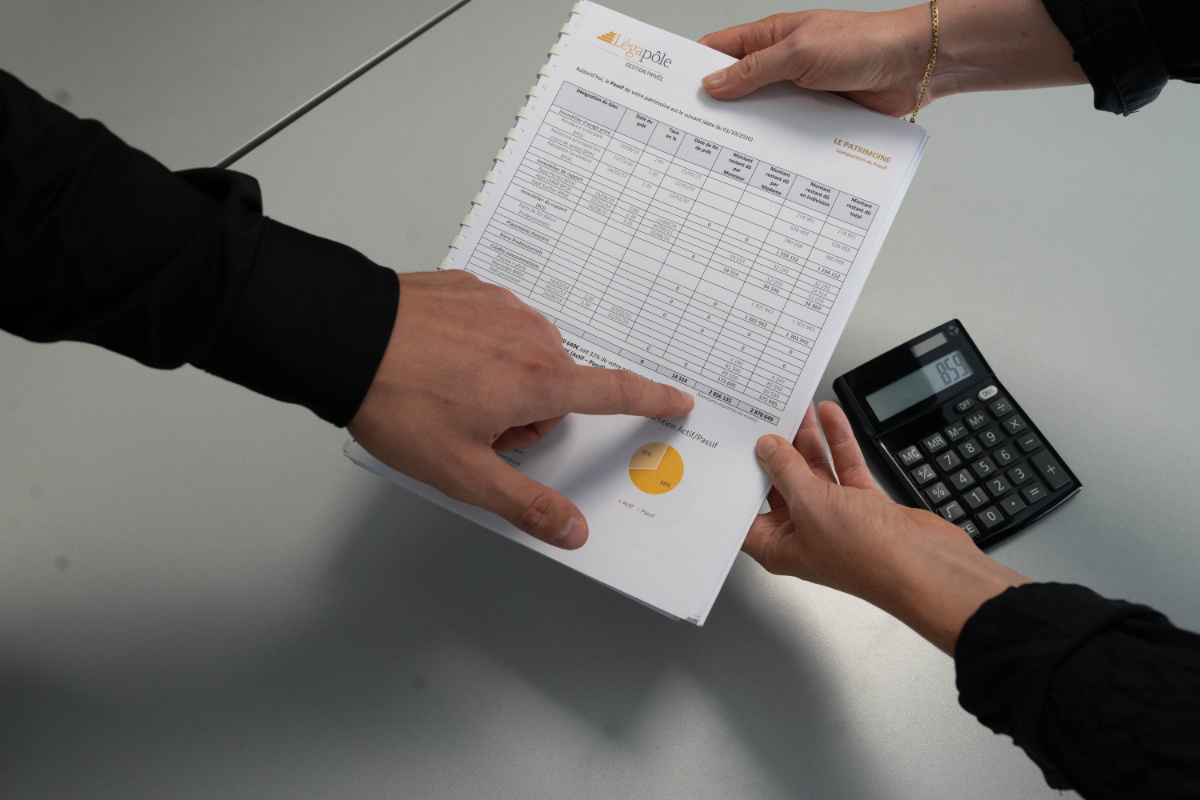 Deux personnes examinent un document financier avec un calculateur.